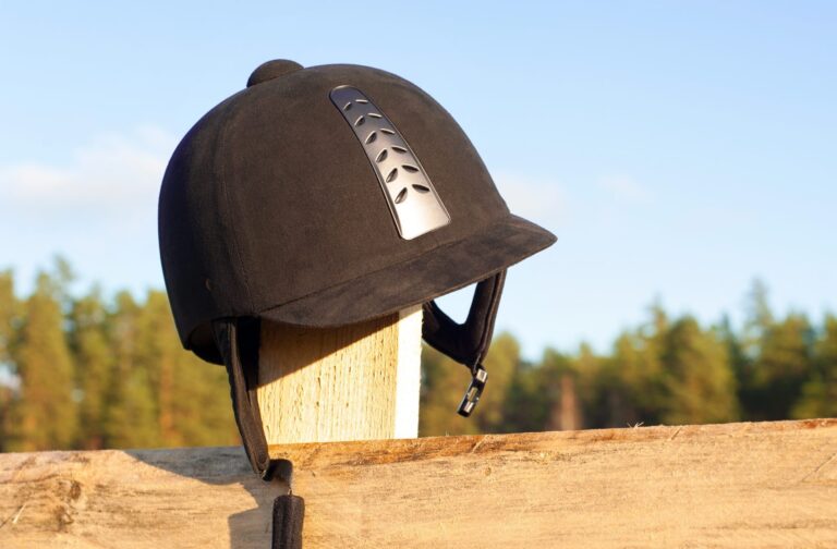 Equestrian helmet forgotten hanging on the wooden fence