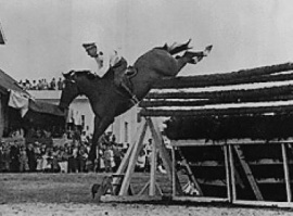 Black and white image of a horse and rider jumping a 8-foot obstacle, setting a world record.