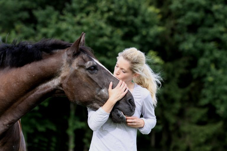 A woman hugging the face of an older horse