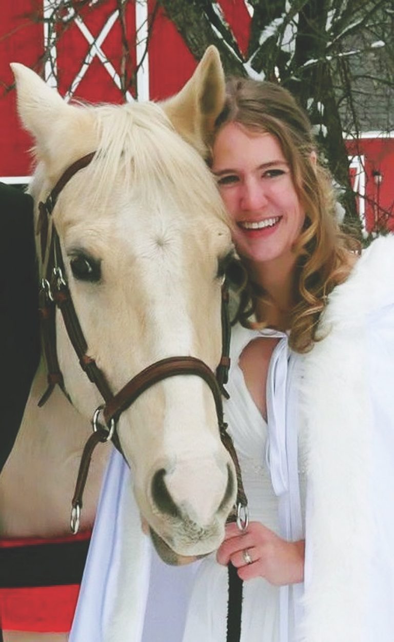 Woman posing with palomino horse