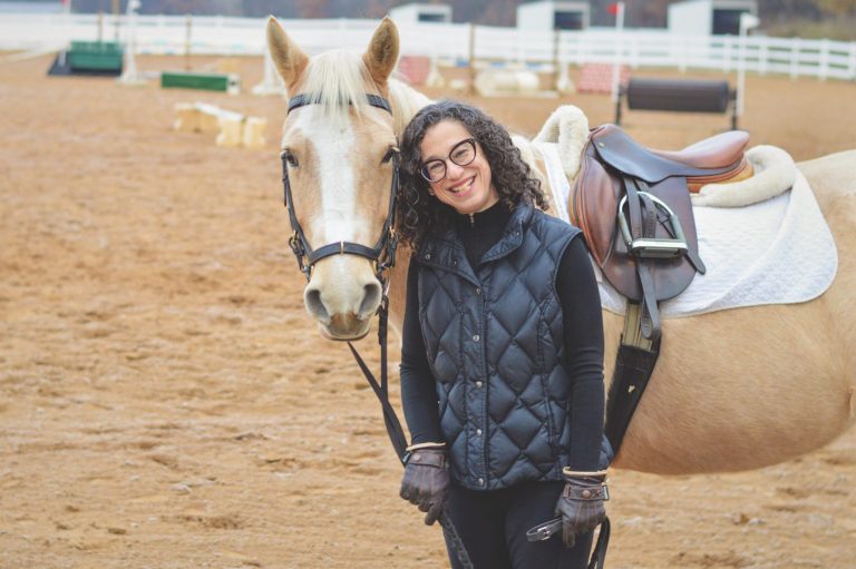 Woman posing with palomino horse