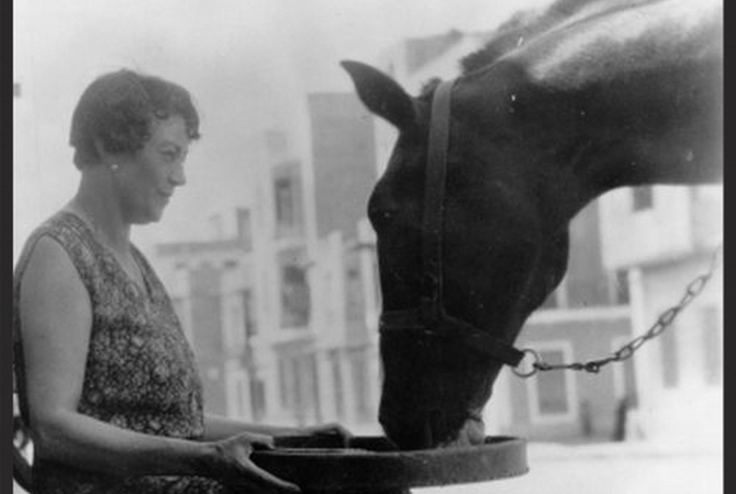 Black and white image of woman feeding horse