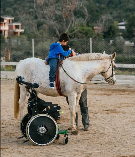 Boy with disabilities embracing his equine therapy instructor at equestrian center