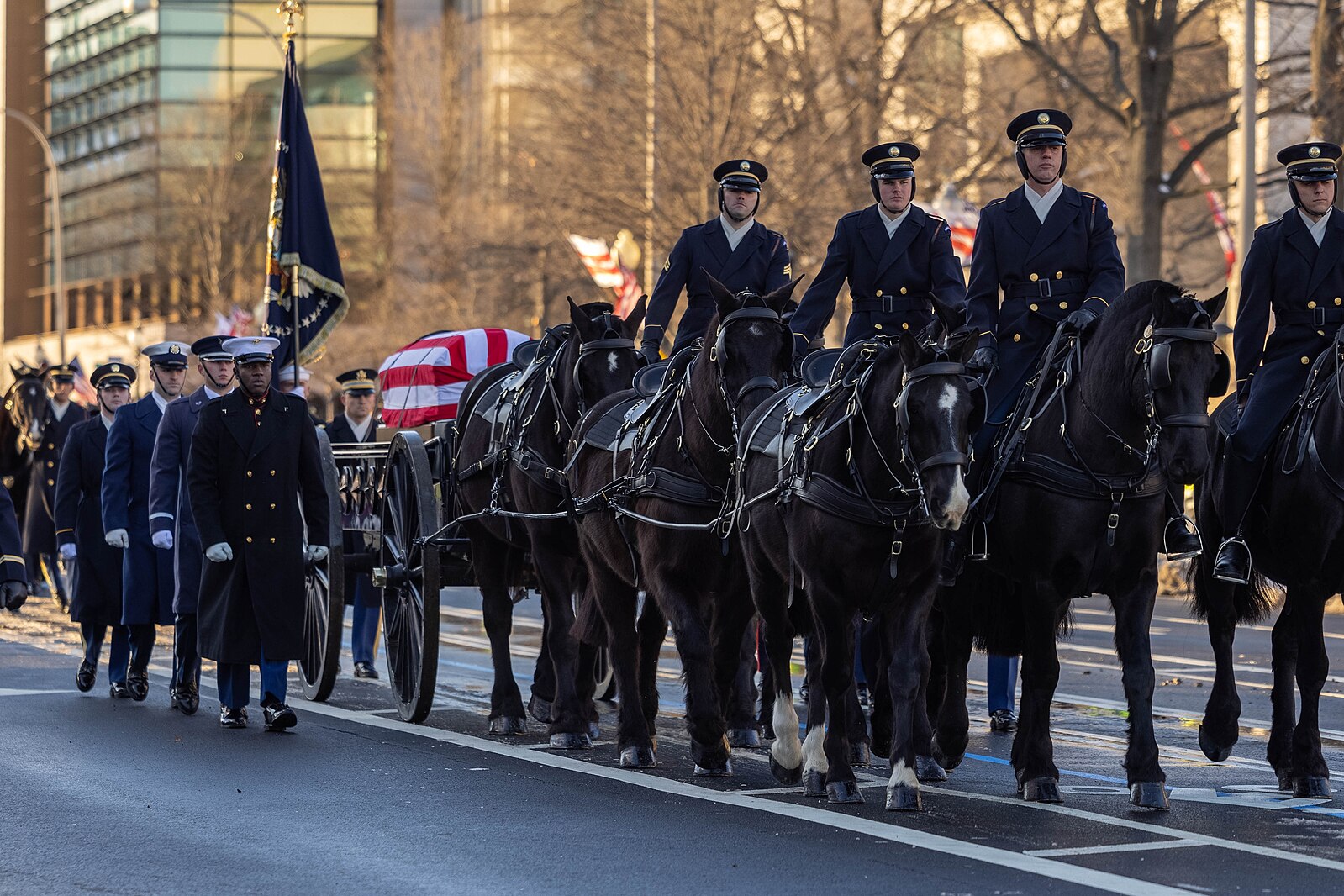 Army caisson detachment walking with horses drawing caisson and flag-draped coffin