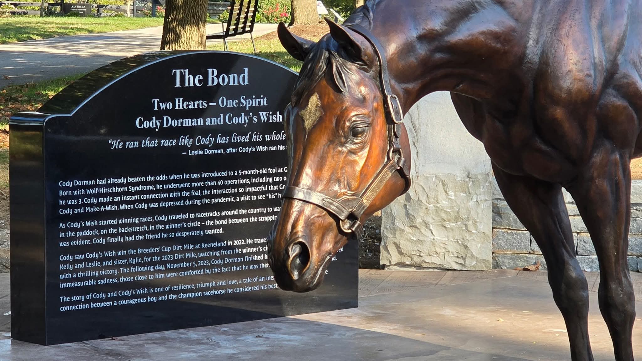 Closeup of the front of a bronze statue of Thoroughbred Cody's Wish next to the plaque in the artistic installation "The Bond"