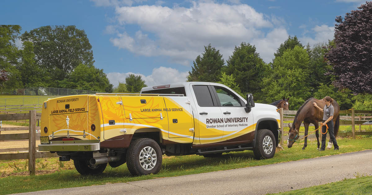 Yellow and white mobile vet truck flanked by woman holding horse