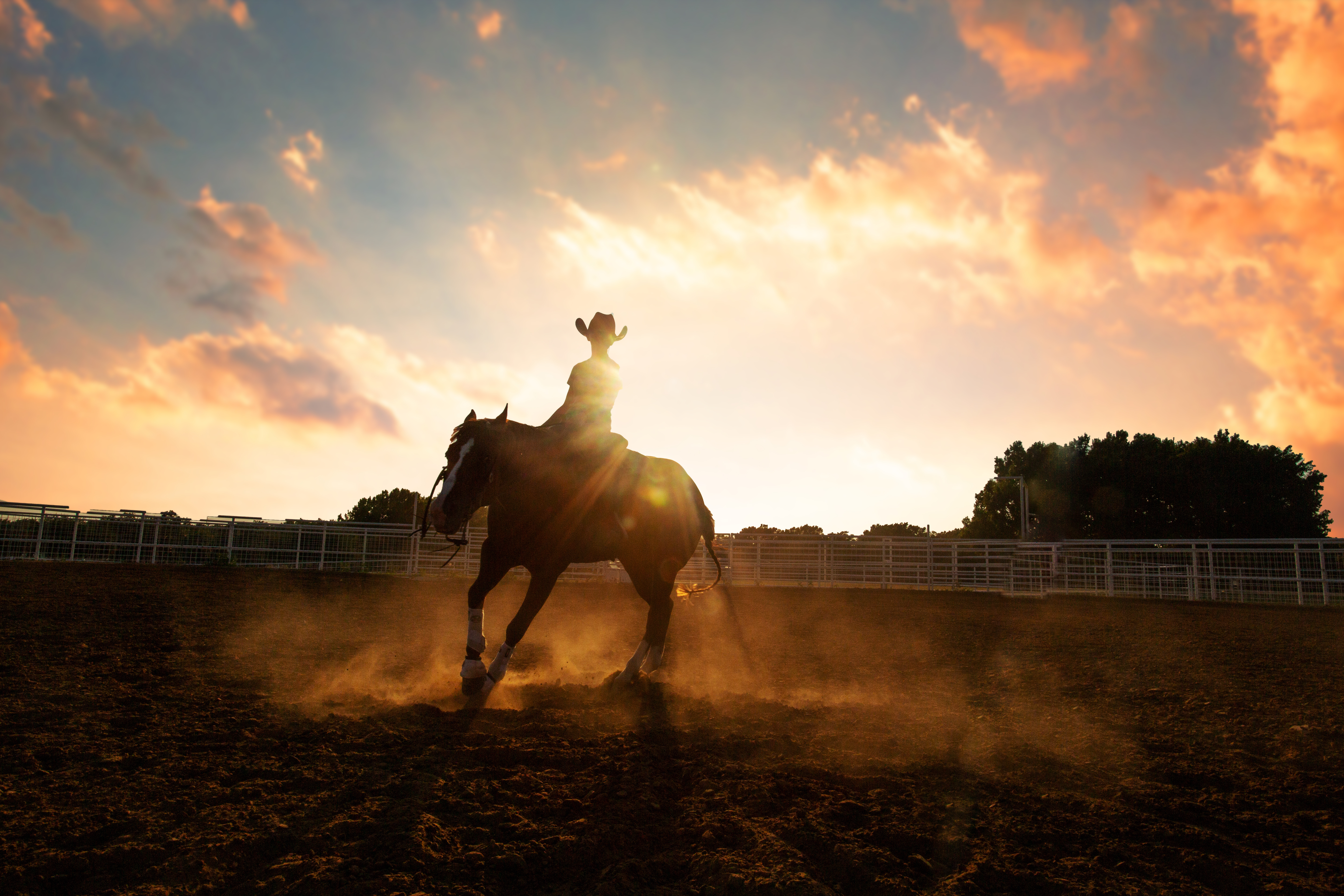 A woman riding western with a dramatic sunrise sky behind her